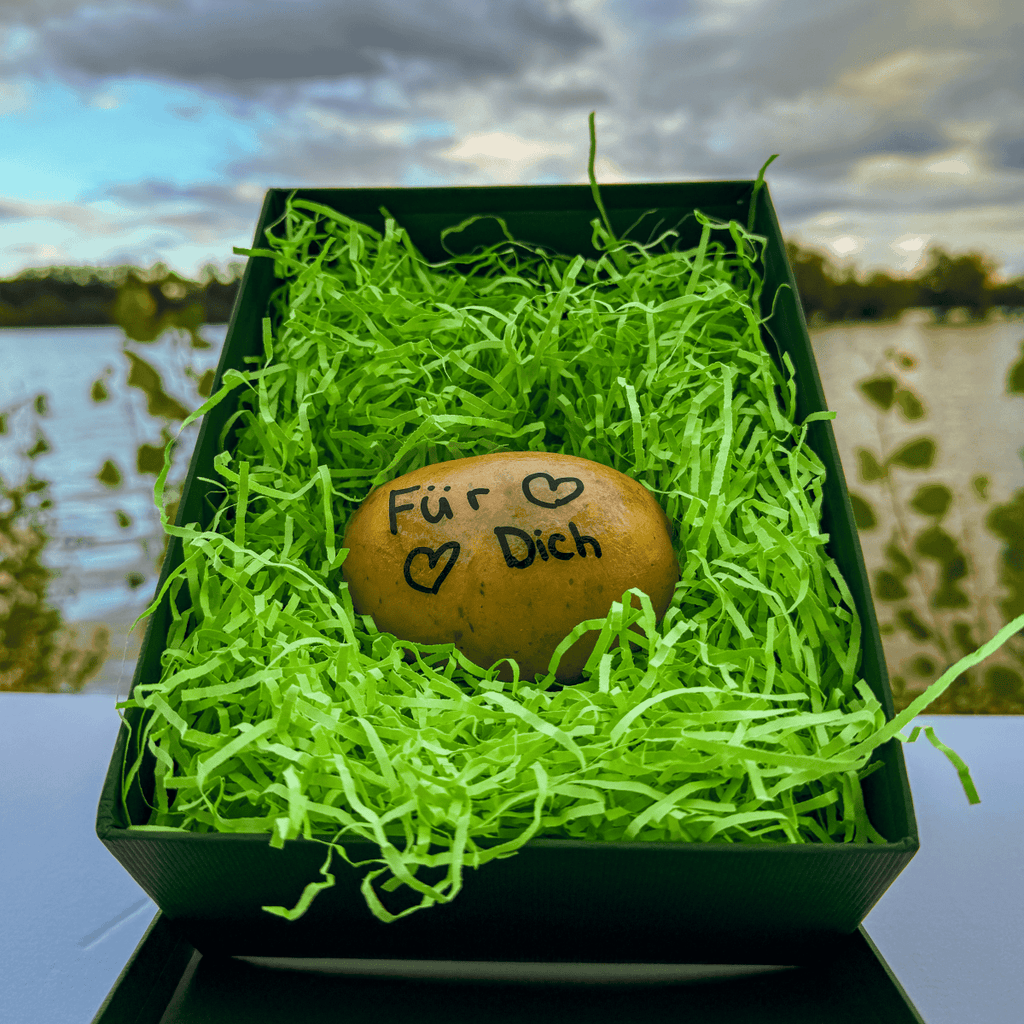 Potato with Text written on in lying in a Box on green fluff. The text says "For You"