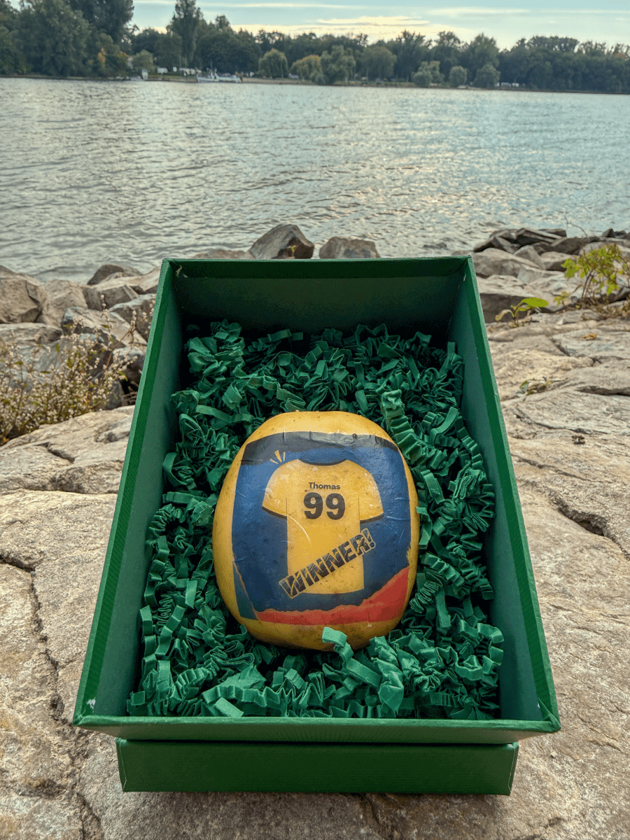 A potato with an image of a football shirt and the word "winner" is lying in a box.